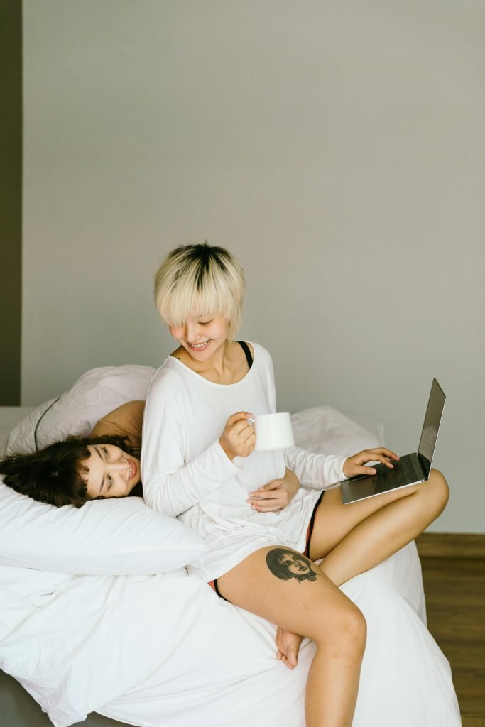 Two women sitting in bed looking at their computer